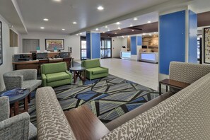 A hotel lobby with seating areas, a reception desk, and a kitchenette.