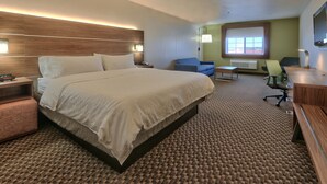Una habitación de hotel con una cama grande, un escritorio, una silla y una mesita.