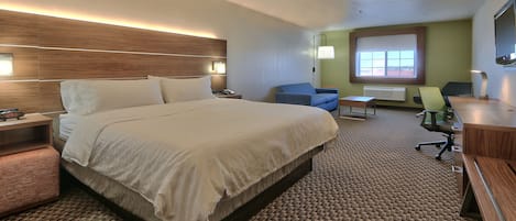 A hotel room with a large bed, a desk, a chair, and a small table.