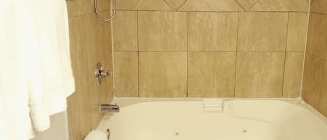 A bathroom with a white bathtub, a towel rack, and a shower head.