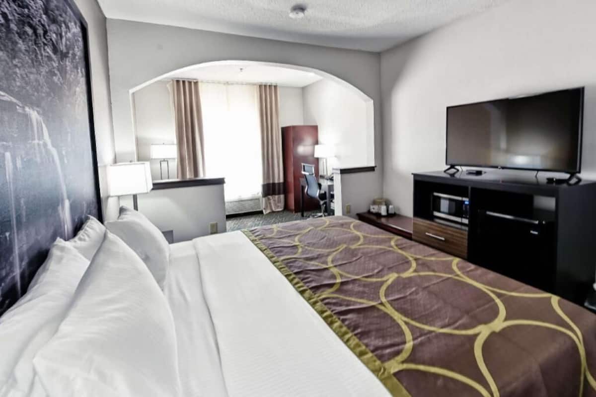 Ein Hotelzimmer mit Bett, Fernseher, Schreibtisch und einem Spiegel im Badezimmer.