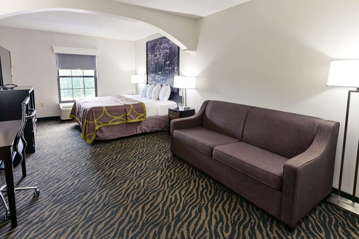 Ein Hotelzimmer mit einem Bett, einem Sofa, einem Schreibtisch und einem großen Fenster.