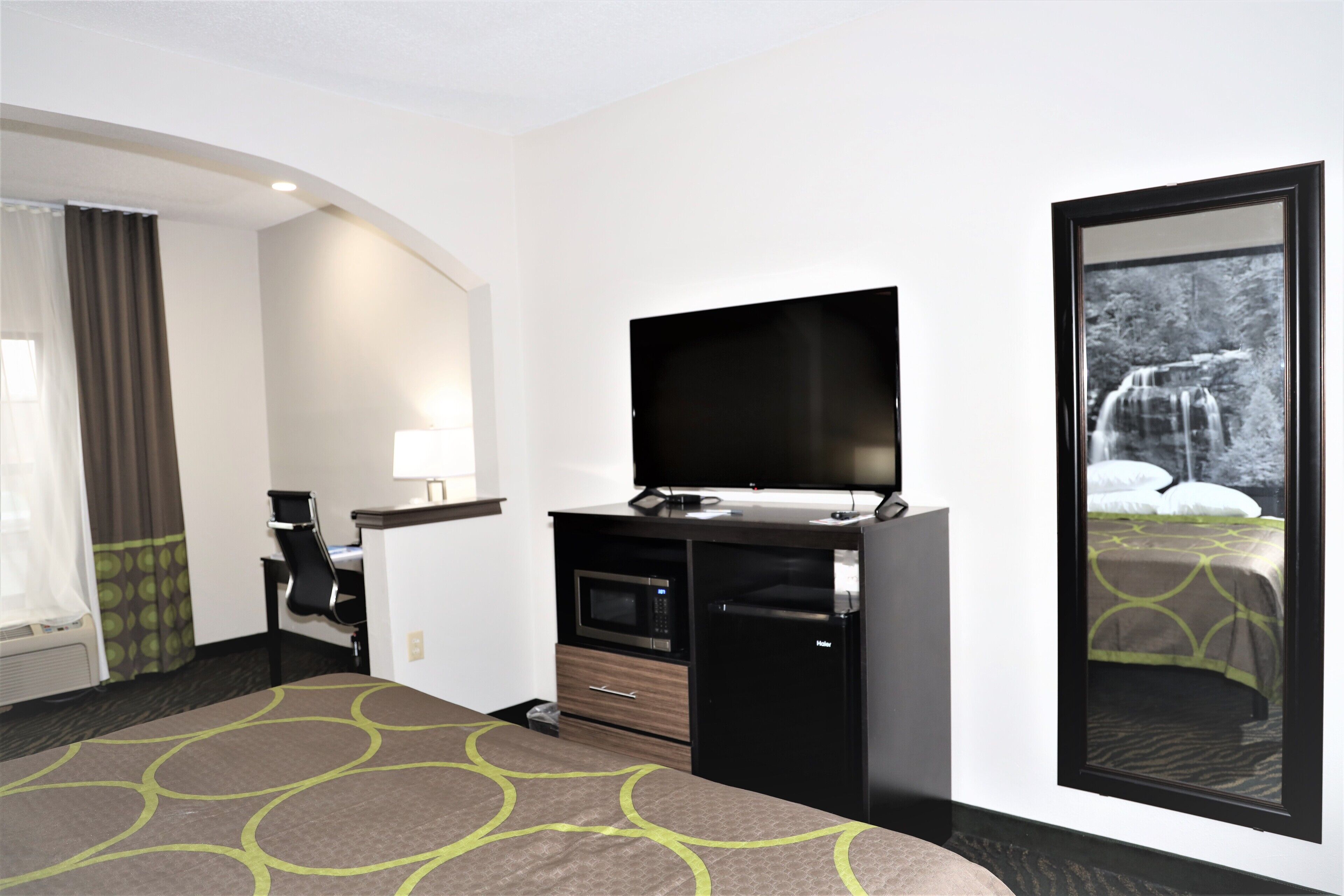 Habitación de hotel con cama, televisor, microondas, refrigerador, escritorio y ventana con vista a una cascada.