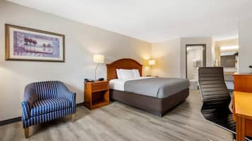 Ein Hotelzimmer mit Bett, Stuhl, Schreibtisch und einem durchgehenden Tür sichtbaren Badezimmer.