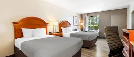 Habitación de hotel con dos camas, un escritorio, una silla y vistas a zonas verdes.