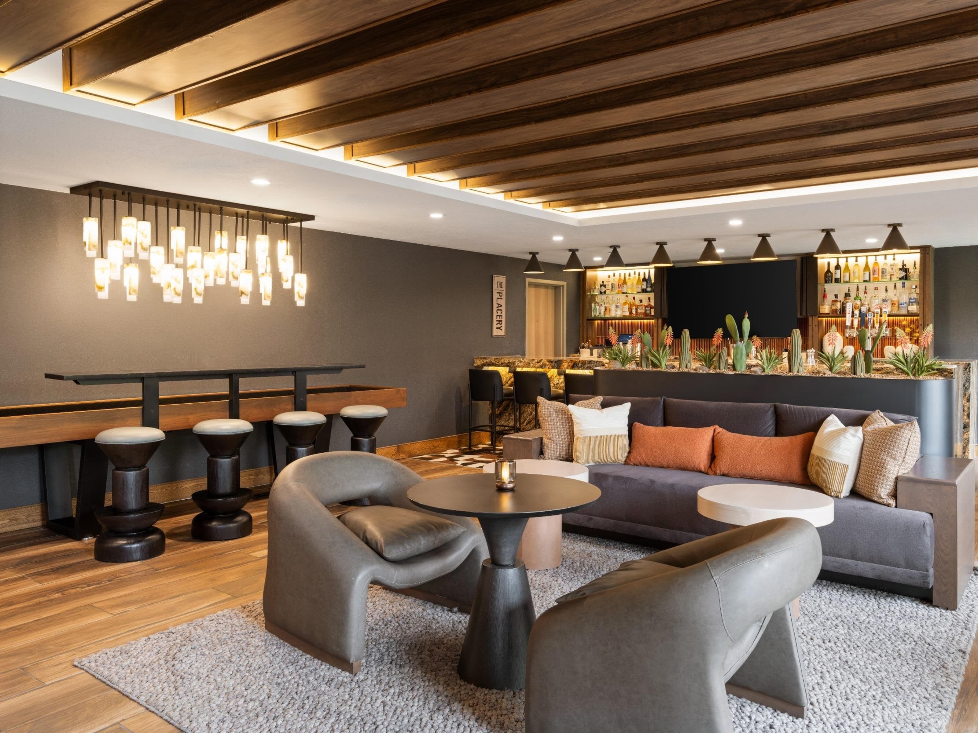 Un espace bar moderne avec un plafond en bois, des tabourets de bar, un canapé et une table ronde.
