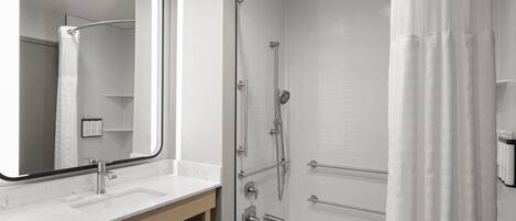 A modern bathroom with a glass-enclosed shower, a white sink, and a large mirror.
