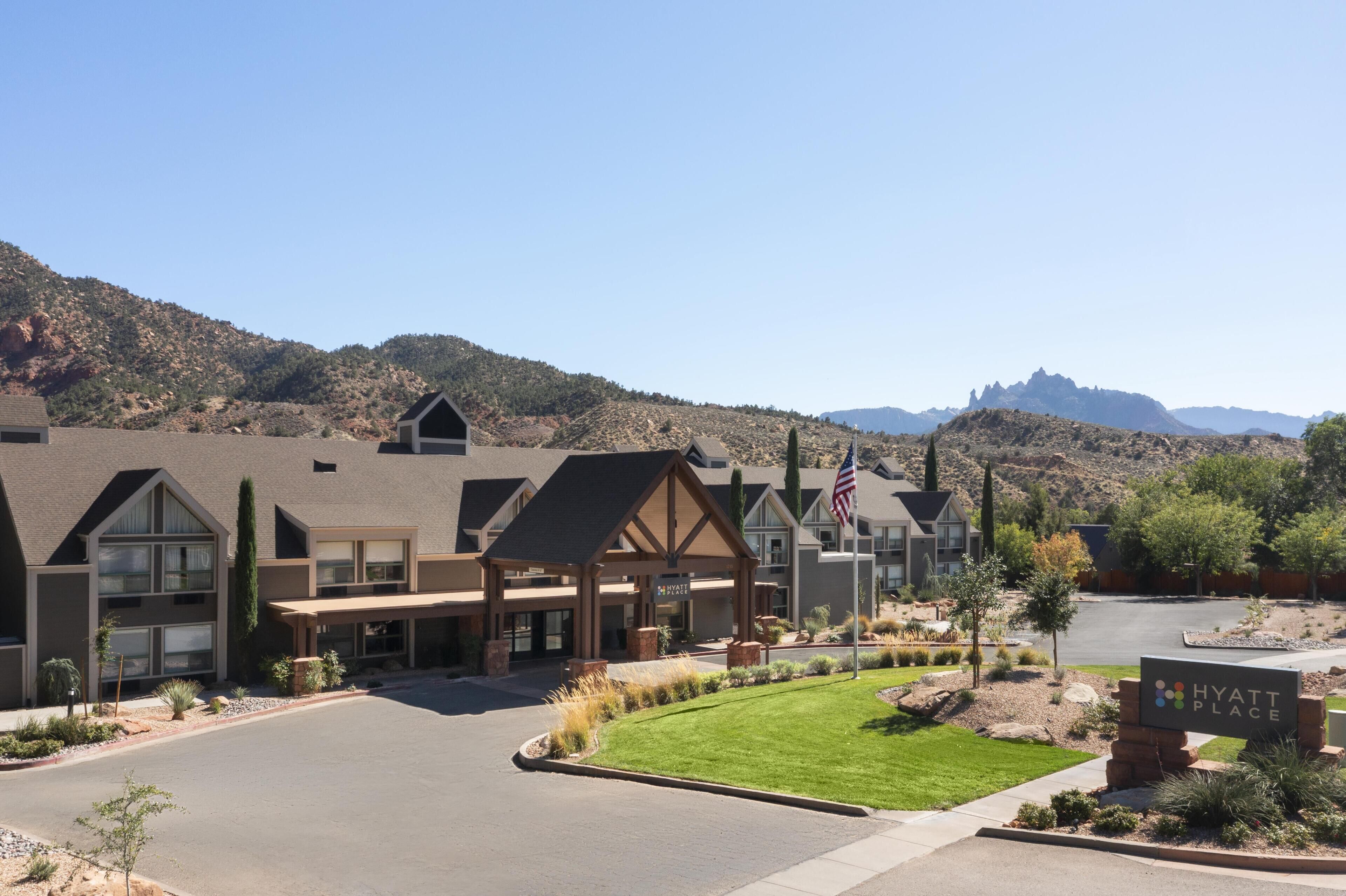 A hotel with a modern design, featuring a covered entrance and a well-maintained lawn.