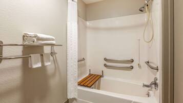 Ein modernes Badezimmer mit Badewanne, Dusche und Haltegriffen.