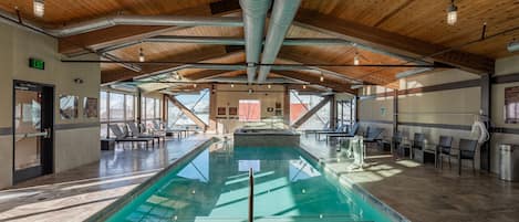 A large indoor swimming pool with a wooden ceiling and clear glass walls.