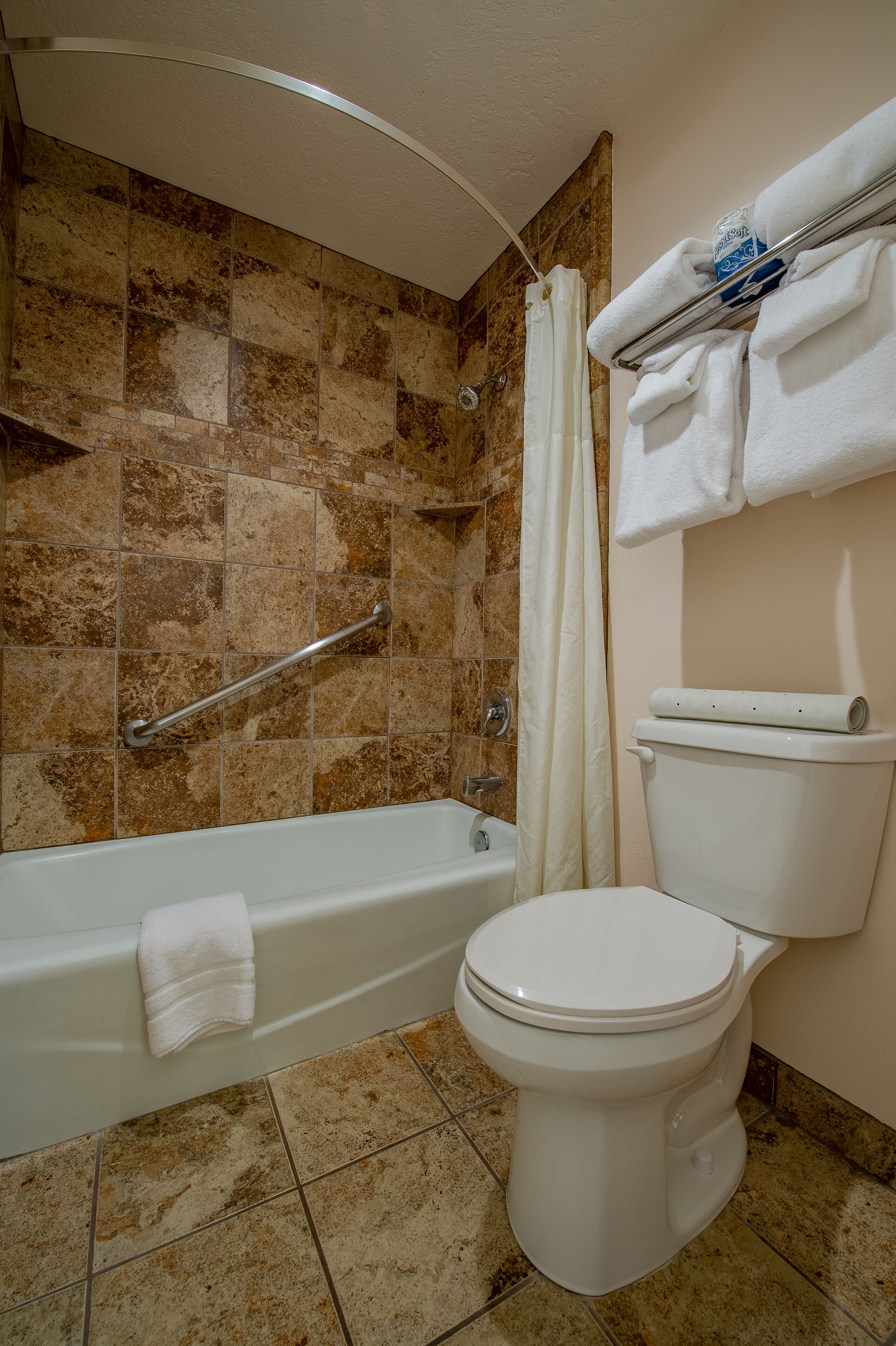 A bathroom with a bathtub, toilet, and shower area.
