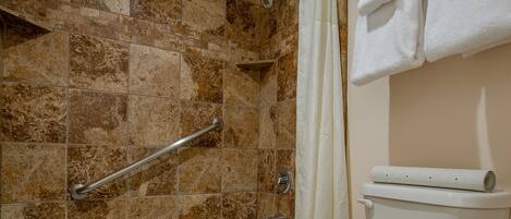 A bathroom with a bathtub, toilet, and shower area.