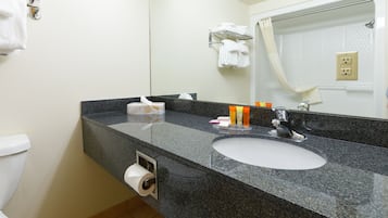A bathroom with a granite countertop, a white sink, a mirror, and a towel rack.