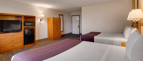 Habitación de hotel con dos camas, televisión, microondas y armario.