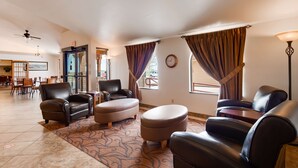 A spacious living room with leather sofas, a patterned rug, and a dining area with wooden chairs and tables.