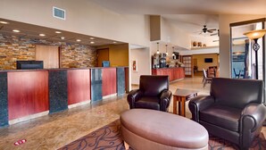A hotel lobby with a reception desk, leather seating, a coffee bar, and a large window.