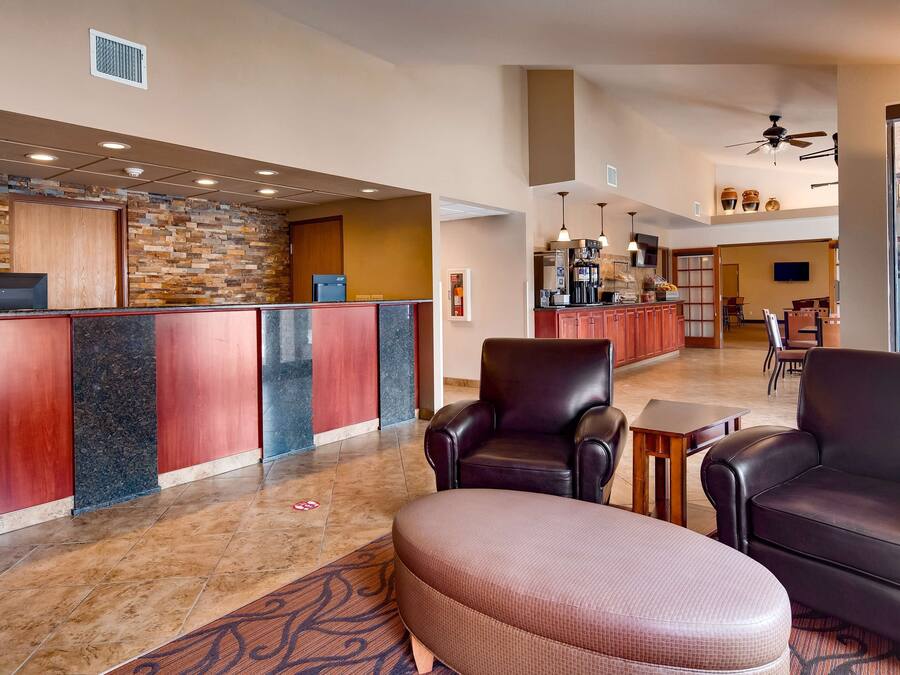 A hotel lobby with a reception desk, leather seating, a coffee bar, and a large window.