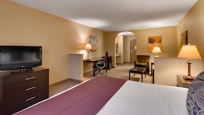 A hotel room with a bed, a TV, a desk with a chair, and a lamp.