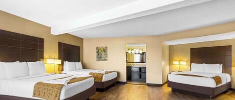A hotel room with two beds, a kitchenette, and a bathroom.