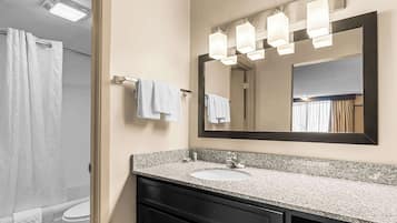 A bathroom with a granite countertop sink, a large mirror, and a towel rack.