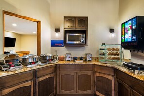 A hotel kitchen with a microwave, toaster, and a digital menu board.