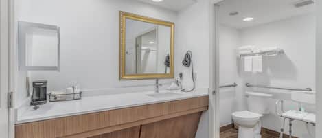 A modern bathroom with a wooden vanity, a large mirror, a toilet, and a shower area.