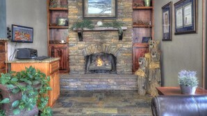A stone fireplace with a clock above it, surrounded by shelves with decorative items and a mounted picture.