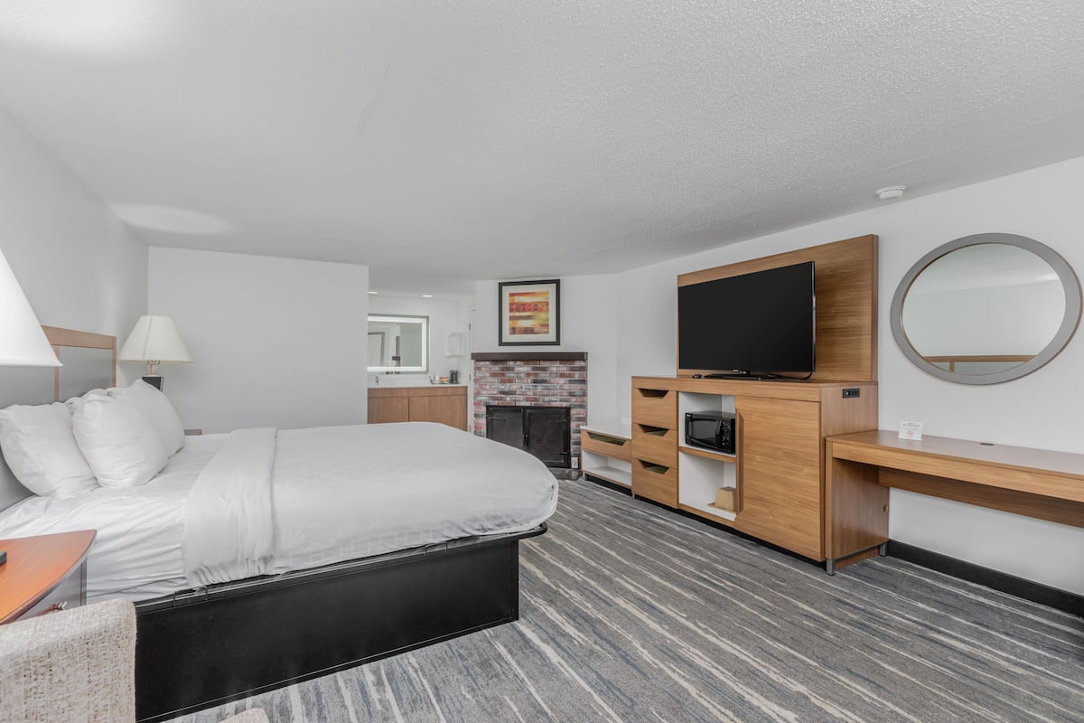 Ein modernes Hotelzimmer mit einem großen Bett, einem Flachbildfernseher, einem Kamin und einem Holztisch.