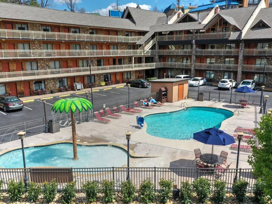 A hotel with a pool area, outdoor seating, and a parking lot.
