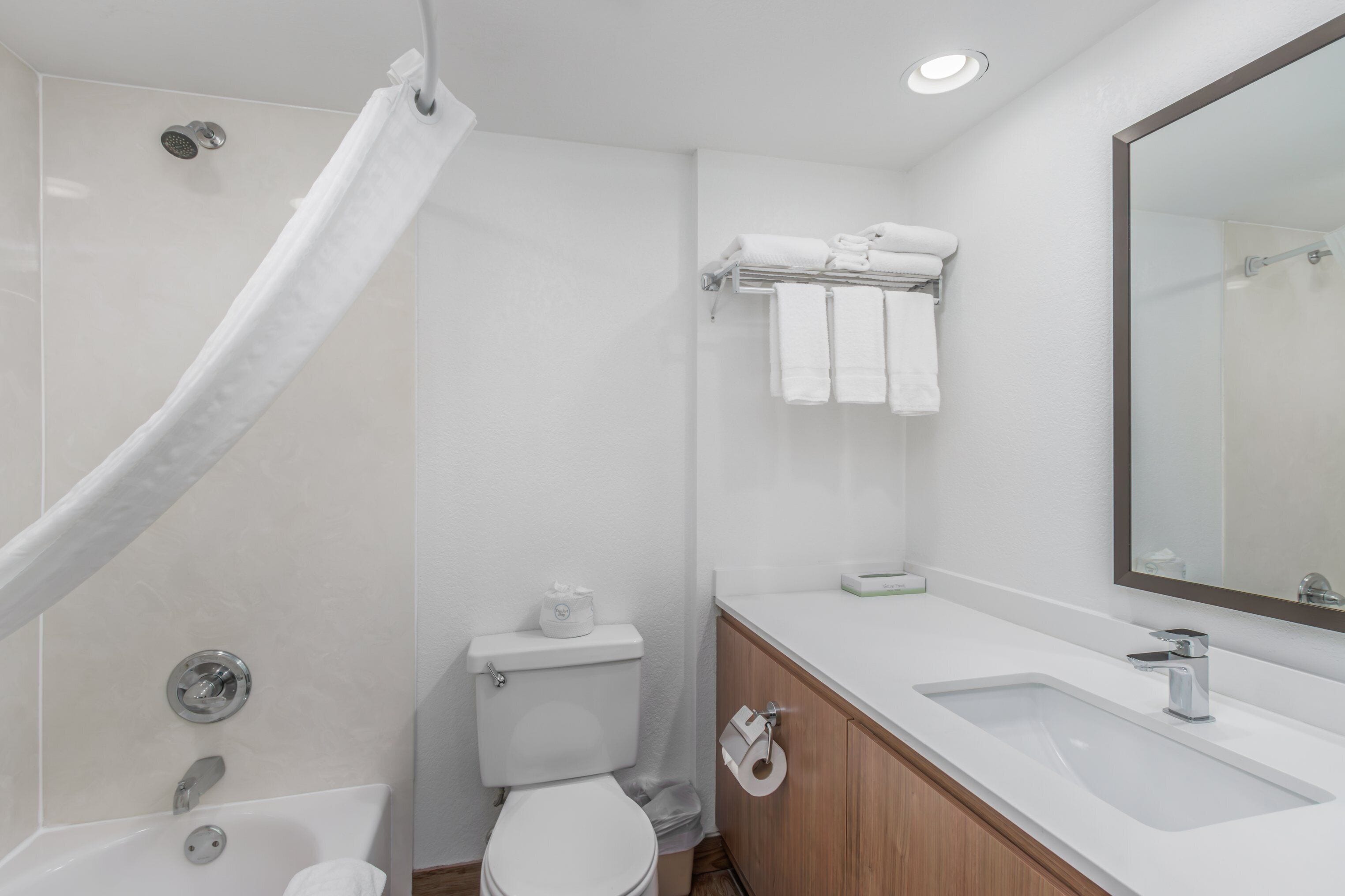 A modern bathroom with a bathtub, toilet, sink, and a mirror.