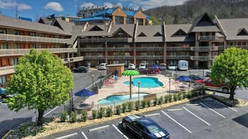 A multi-story hotel with a pool area, outdoor seating, and a parking lot.
