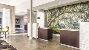 A modern lobby with a reception desk, a large mural of trees, and a seating area with chairs. - La Quinta Inn & Suites by Wyndham Alexandria Airport (Alexandria)