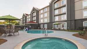 A hotel with a swimming pool, outdoor seating, and a covered patio area. - La Quinta Inn & Suites by Wyndham Alexandria Airport (Alexandria)