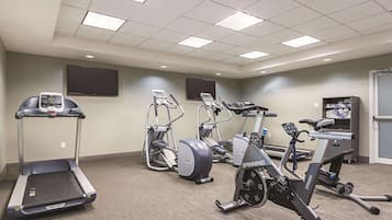 Un gimnasio con cintas de correr, elípticas y bicicletas estáticas.