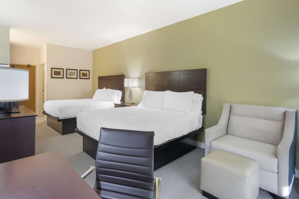 Una habitación de hotel con cama, dos mesitas de noche, un escritorio, una silla y televisor.