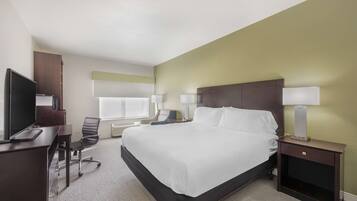 A hotel room with a large bed, a desk with a computer, a chair, and two bedside lamps.