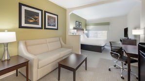 A hotel room with a sofa, a desk, a chair, a bed, and two framed pictures on the wall. - Best Western Celina (Celina)