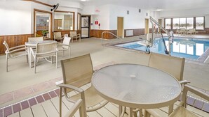 An indoor pool area with a glass table and chairs, a pool ladder, and a view of the beach through large windows. - Best Western Celina (Celina)