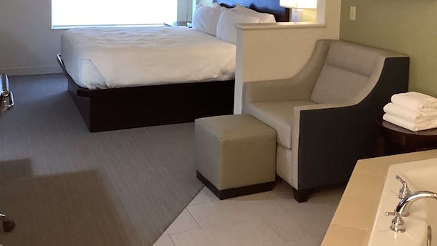 A hotel room with a double bed, a sofa bed, a small table, a chair, a desk, and a bathroom with a sink and mirror. - Best Western Celina (Celina)