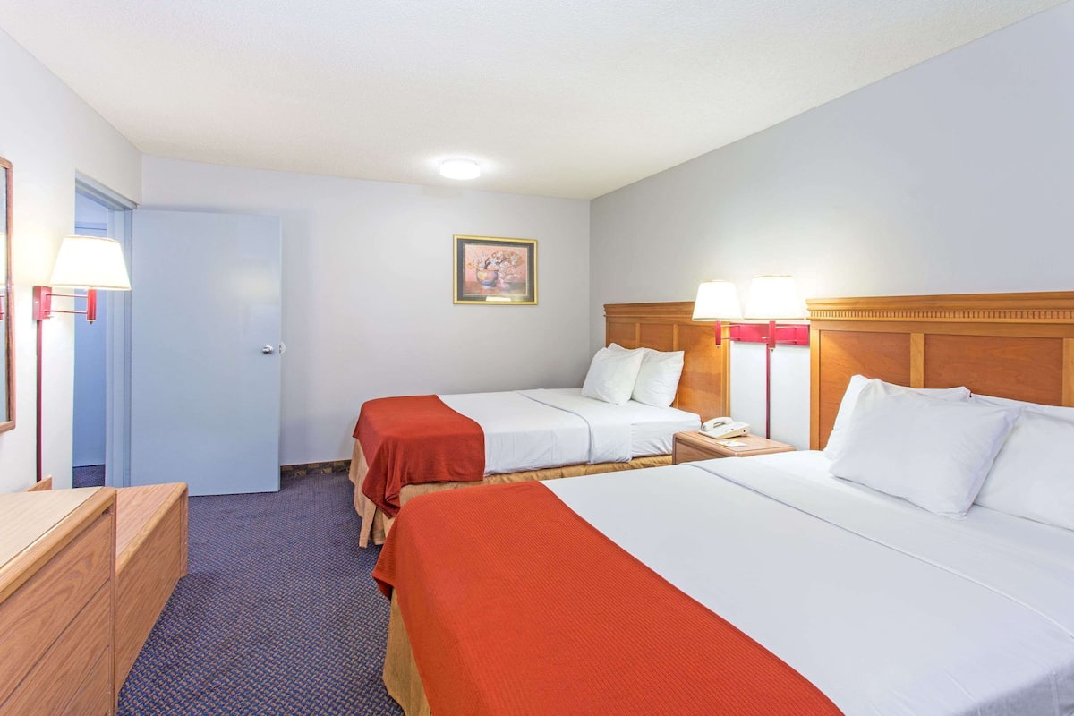 Ett hotellrum med två sängar, ett skrivbord, en stol och en dörr.