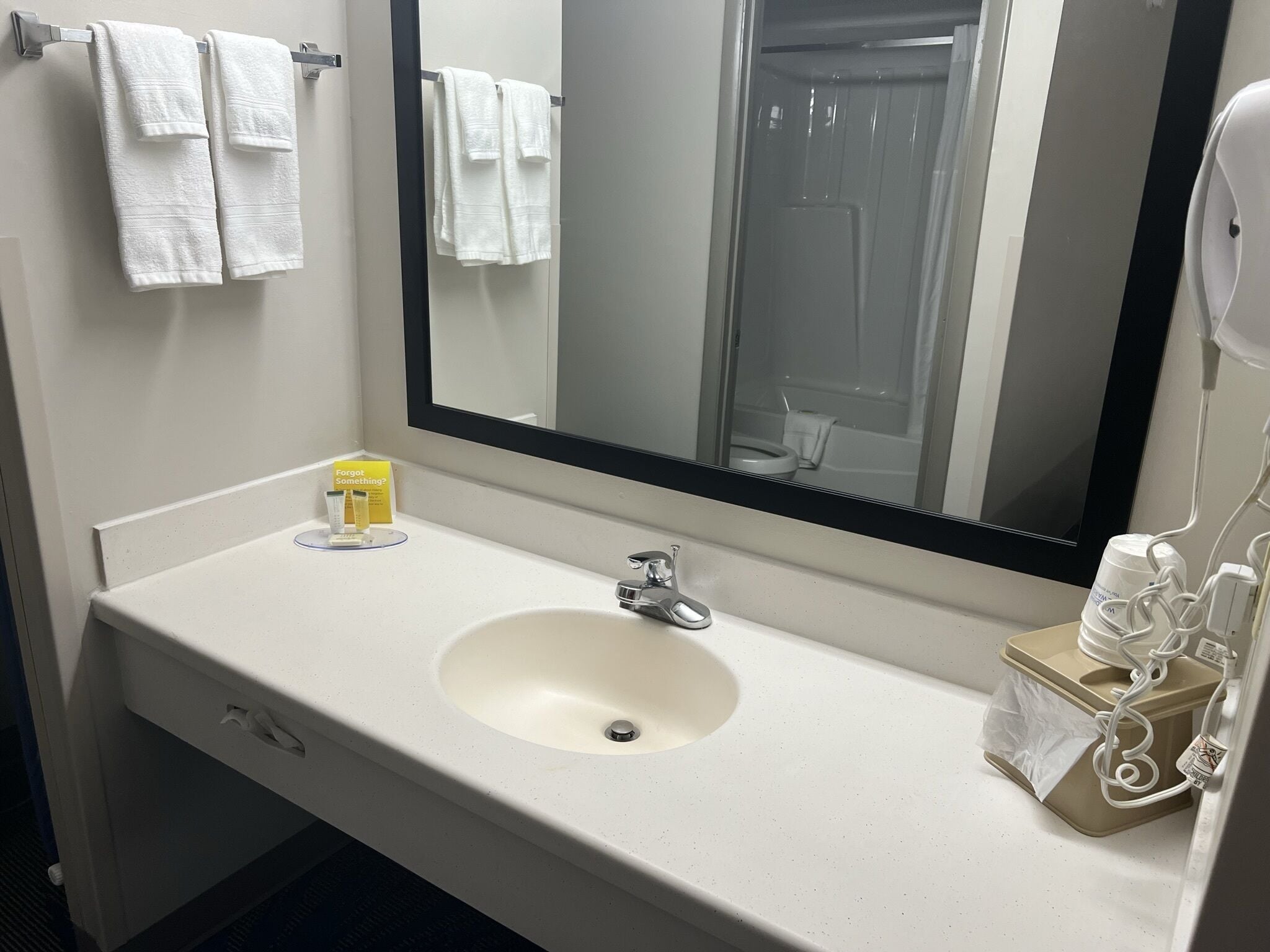A hotel bathroom with a white sink, a mirror, and two white towels hanging on a towel rack.