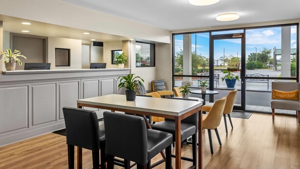 A modern dining area with a large table, chairs, and potted plants. -  Days Inn by Wyndham Valdosta I-75 (Valdosta)