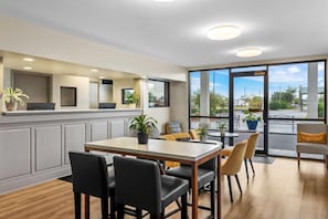 A modern dining area with a large table, chairs, and potted plants.