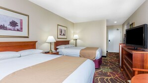 Quarto de hotel com duas camas, televisão, escrivaninha e uma cadeira.