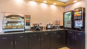 Uma cozinha com máquina de café, dispensador de alimentos e geladeira.