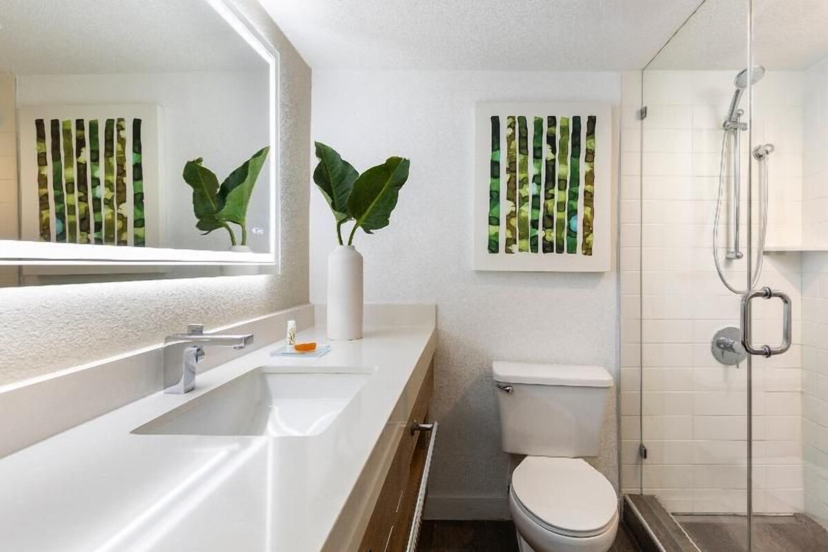 A modern bathroom with a white sink, toilet, and shower.