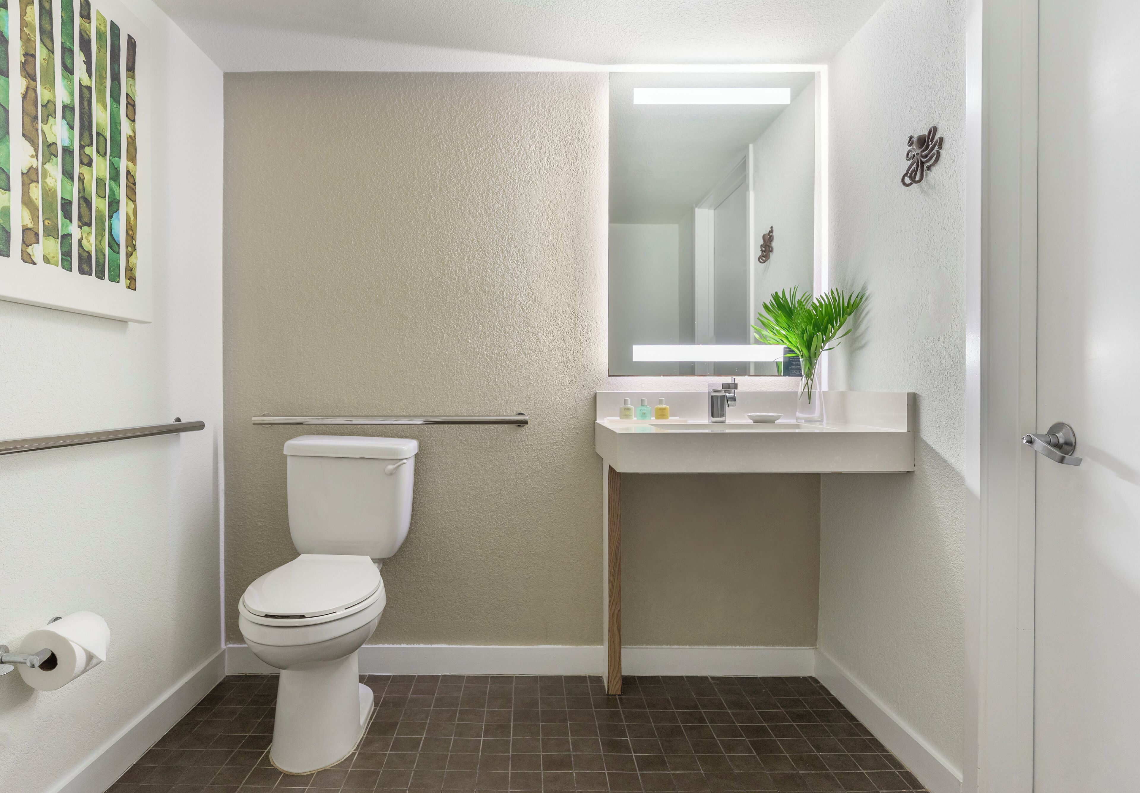 A bathroom with a toilet, a sink with a mirror, and a towel rack.