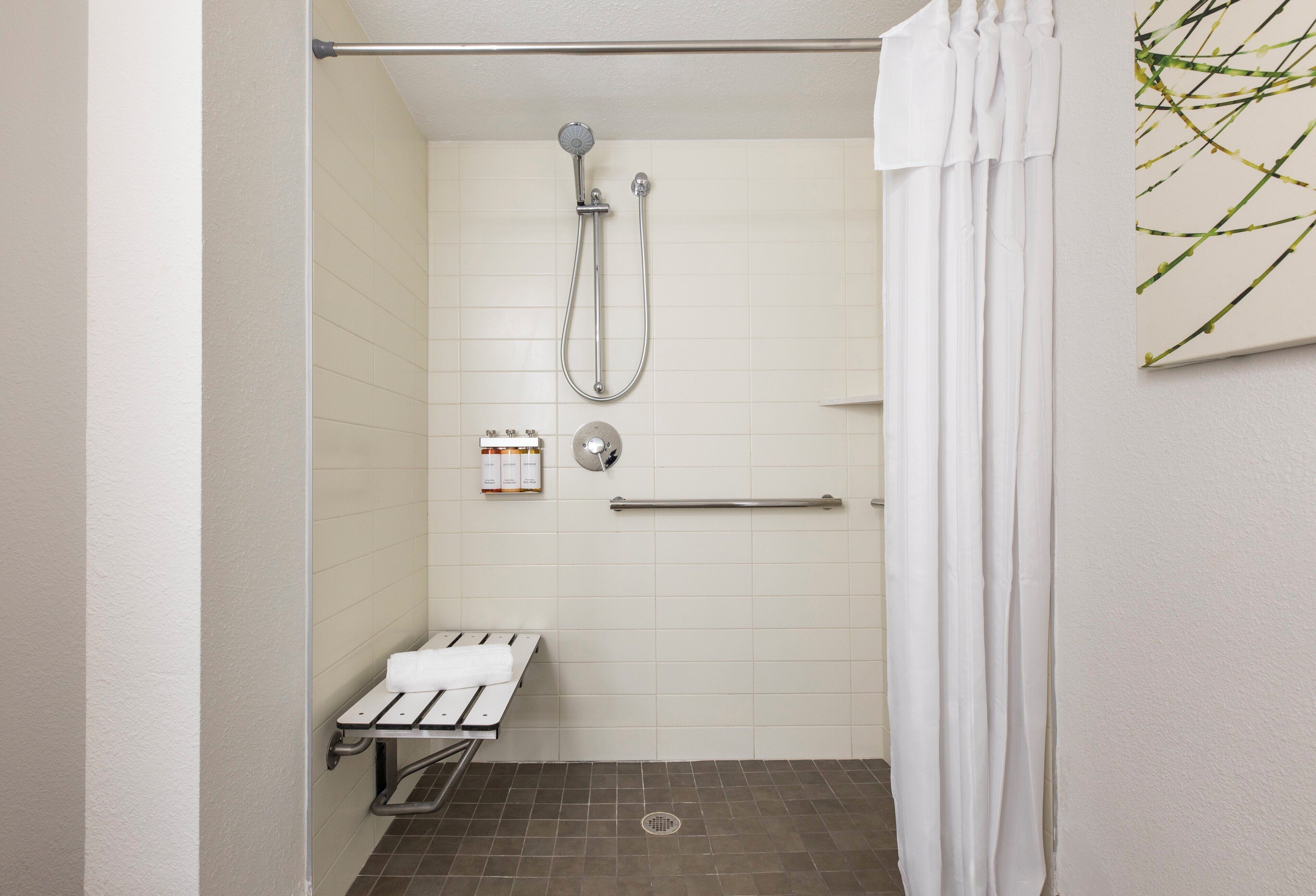 Un espace douche équipé d’un pommeau de douche à main, d’un porte-serviettes et d’un petit banc.