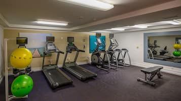 A gym with treadmills, elliptical machines, and exercise balls.