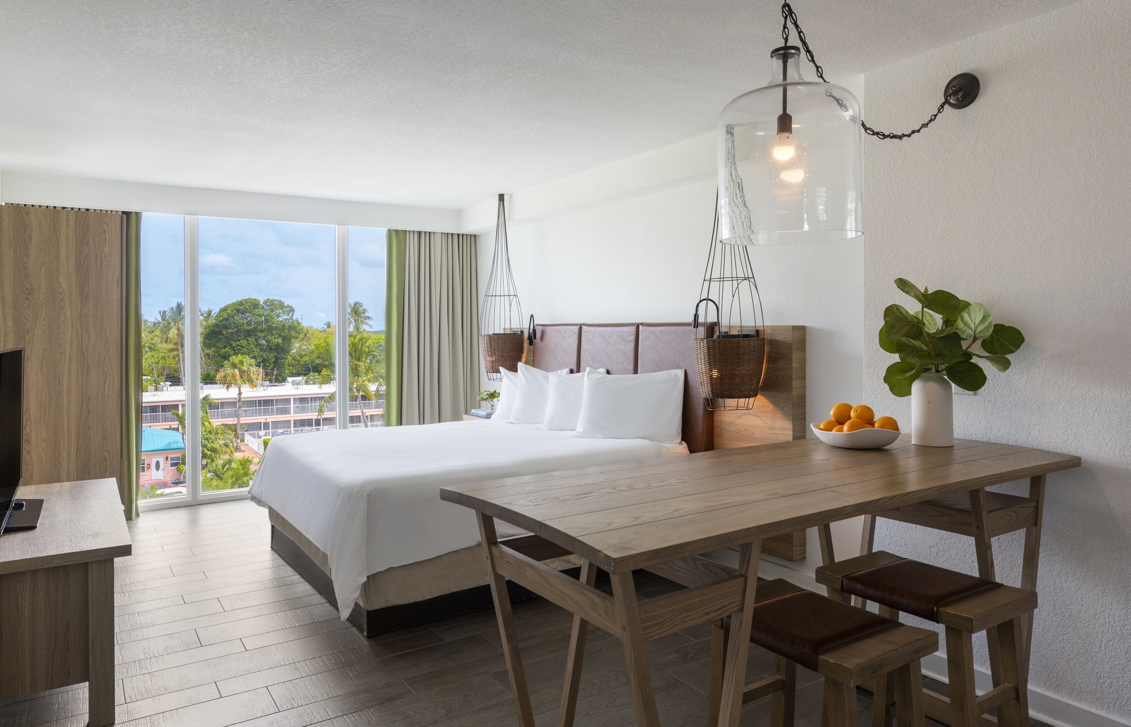 A hotel room with a large bed, wooden desk, and bench seating.